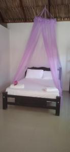 a bed with a purple mosquito net in a room at Las Flores Econativo in Isla Grande