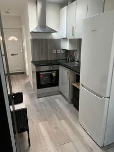 cocina con armarios blancos y nevera blanca en Modern Studio flat with free parking, en Langley Marish