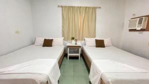 2 Betten in einem Zimmer mit einem Tisch und einem Fenster in der Unterkunft Manalo's Lodge and Restaurant in Puerto Galera