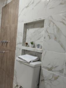 Baño blanco con aseo y pared de mármol en Departamento en Posadas, en Posadas