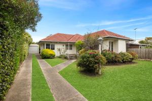 een huis met een groene tuin met een oprit bij Price Central Torquay 32 in Torquay