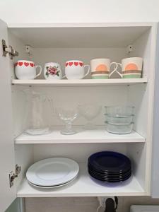 a white shelf with plates and cups and dishes at Flat near the Vyšehrad Castle in Prague