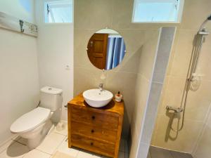La salle de bains est pourvue d'un lavabo, de toilettes et d'un miroir. dans l'établissement Bungalow Tiare, à Uturoa
