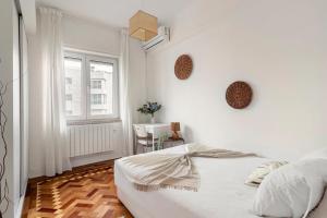 een witte slaapkamer met een bed en een raam bij Soar Home in Lissabon