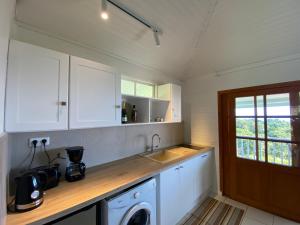 a kitchen with white cabinets and a washing machine at Bungalow Tiare in Uturoa
