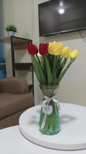 Pagadian Staycation in Camella 1 في باجاديان: مزهرية مليئة بالزهور الأحمر والأصفر على الطاولة