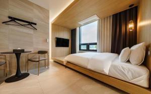 a bedroom with a bed and a table and a window at The Line Hotel in Yangpyeong