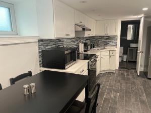 a kitchen with white cabinets and a black counter top at Modern & cozy Room in Queens near Train station and buses in Woodhaven