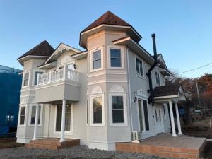 uma grande casa branca com uma varanda em Queen Anne Style Luxury Vacation Villa em Miyota