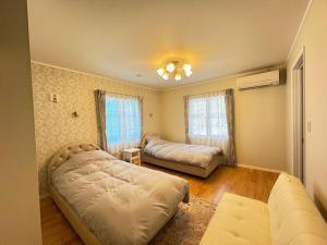 a bedroom with two beds and a couch at Queen Anne Style Luxury Vacation Villa in Miyota