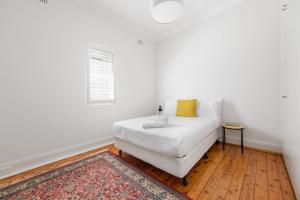 a white bedroom with a white couch and a window at WINCH9 - Seaside Serenity in Sydney