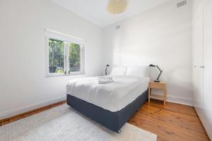 a white bedroom with a bed and a window at WINCH9 - Seaside Serenity in Sydney