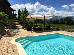 a swimming pool with people sitting in chairs next to a house at "La Coustille" Chambres et Table d'Hôtes in Saint-Léger-les-Mélèzes