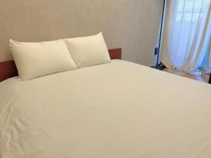 東京的住宿－Book Tea Bed SHINJUKU-GYOEN，白色的床、白色枕头和窗户