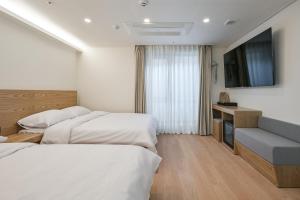 a hotel room with two beds and a flat screen tv at Seoul N Hostel in Seoul