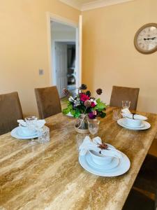 a dining room table with plates and flowers on it at Contractors Home - 4 Bedroom Long Stays Welcome - Barnsley in Shafton +15 photos