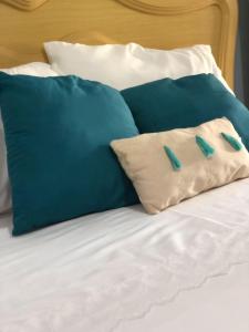 Una cama con almohadas azules y blancas. en Casa confortável em Estancia en Estância