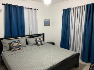 a bedroom with blue curtains and a bed with pillows at Arcus hospedaje in Juan López