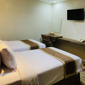 a hotel room with two beds and a television at Travellers Hotel Phinisi in Makassar