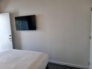 a bedroom with a bed and a flat screen tv on the wall at Lakeview Colonial House in Queenstown