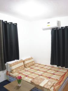 Pagadian Staycation in Camella 2 في باجاديان: سرير في غرفة مع ستائر سوداء وطاولة