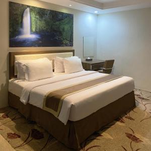 a bedroom with a large bed with a painting on the wall at Travellers Hotel Phinisi in Makassar