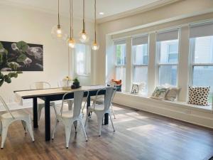 a dining room with a table and chairs and windows at Chic Crosstown Bungalow with large fenced backyard in Memphis