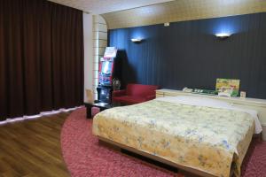 um quarto de hotel com uma cama e uma cadeira vermelha em Hotel Silk no Mori (Adult Only) em Tosu