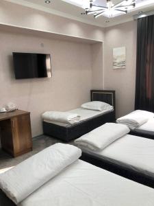 een kamer met 3 bedden en een flatscreen-tv bij Ibn Sino Hotel in Bukhara