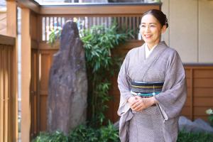 una mujer en un kimono parada frente a un templo en 別所温泉 七草の湯, en Ueda
