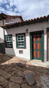 a white house with green and red doors at Casa histórica do escravo isidoro in Diamantina