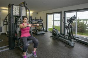 a woman is sitting on a gym machine at Rodd Miramichi in Miramichi