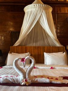 two swans making a heart shape on a bed at Unzipp Bungalows Gili Air in Gili Air