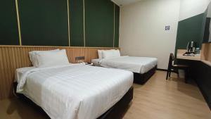 a hotel room with two beds and a table with a chair at Urban Inn, Alor Setar in Alor Setar