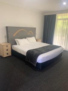 a large bed in a hotel room with a large bed sidx sidx sidx at Leura Gardens Resort in Leura