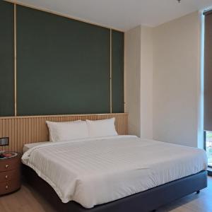 a bedroom with a large white bed with a green wall at Urban Inn, Alor Setar in Alor Setar +83 photos