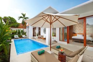 a villa with a swimming pool and an umbrella at The Luxury Collection, Monaco Blu in Seminyak