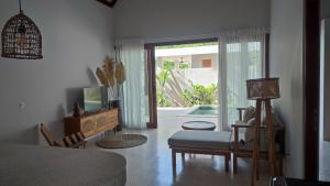 ein Wohnzimmer mit einem Sofa, einem TV und einer Glasschiebetür in der Unterkunft Karyana Villa 1 in Kuta Lombok