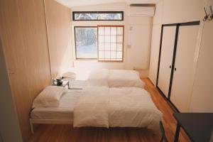 two beds in a small room with a window at HAKUBA76 in Hakuba