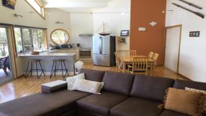 a living room with a couch and a kitchen at Rest A Shore Coffin Bay in Coffin Bay