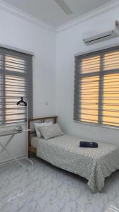 a white room with two beds and a window at Homestay Rumi in Machang