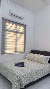 1 dormitorio con 1 cama con mando a distancia en Homestay Rumi, en Macang