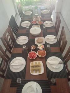 a long wooden table with plates and bowls of food at AMRON RESORT SIGIRIYA in Sigiriya