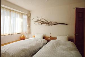 two beds in a room with a branch on the wall at SMALL TOWN HOTEL Hakodate in Hakodate