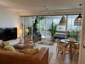 Carramah Noosa Heads apartment في نوسا هيدز: غرفة معيشة مع أريكة وطاولة