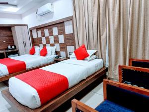 two beds in a hotel room with red and white pillows at Hotel King Castle Central Heated & Air cooled in Dharamshala
