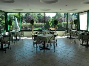 een eetkamer met tafels en stoelen en grote ramen bij Hotel Santin in Bełchatów