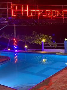 una piscina por la noche con un cartel de neón en DONQUE'S MOUNTAIN RESORT (D'HORIZON), en Samboan