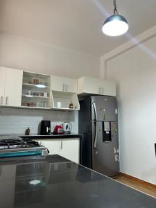eine Küche mit einem schwarzen Kühlschrank und weißen Schränken in der Unterkunft Alojamiento en departamento compartido in Cajamarca