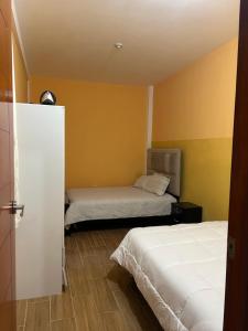 2 Betten in einem Zimmer mit gelben Wänden in der Unterkunft Alojamiento en departamento compartido in Cajamarca